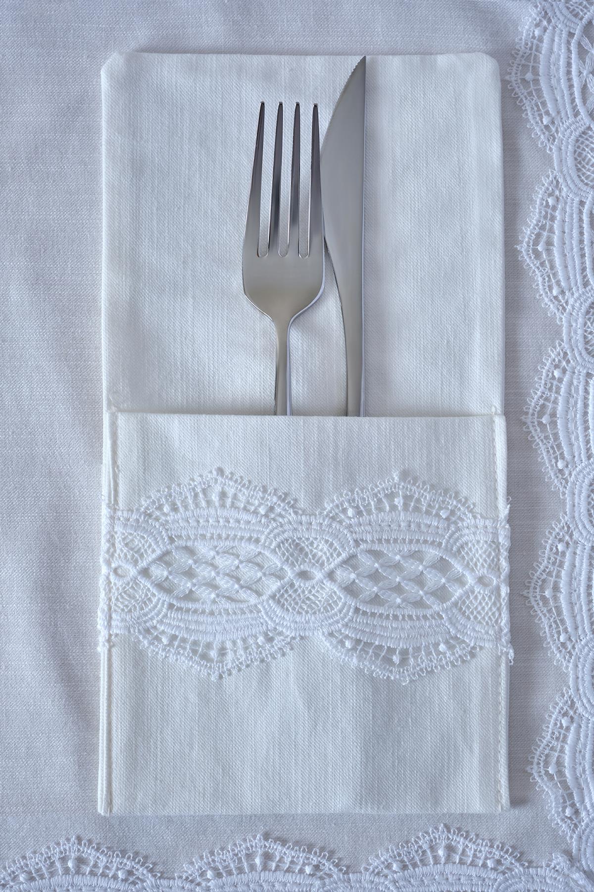Fork and knife on a white napkin with lace detail, elegant table setting