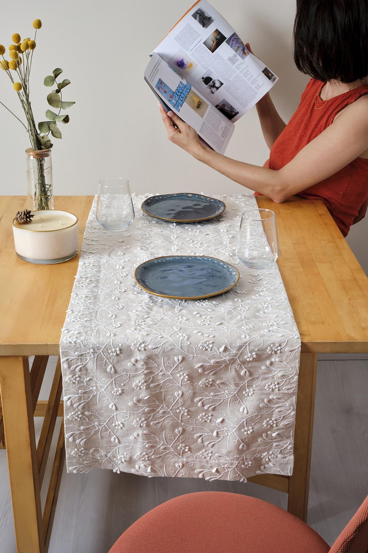 Cream lace table runner on a wooden table, two blue plates, and a stylish decorative table setting