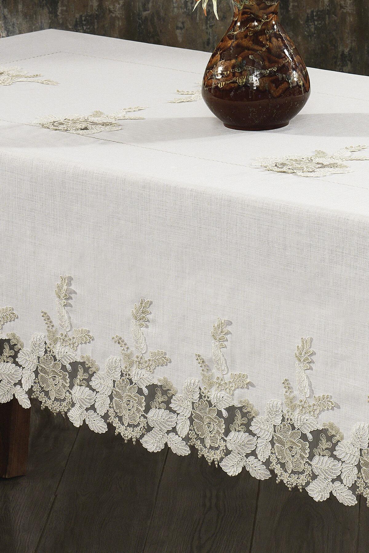 Lace, cream-colored, stain-resistant tablecloth; next to a stylish table and ceramic vase.