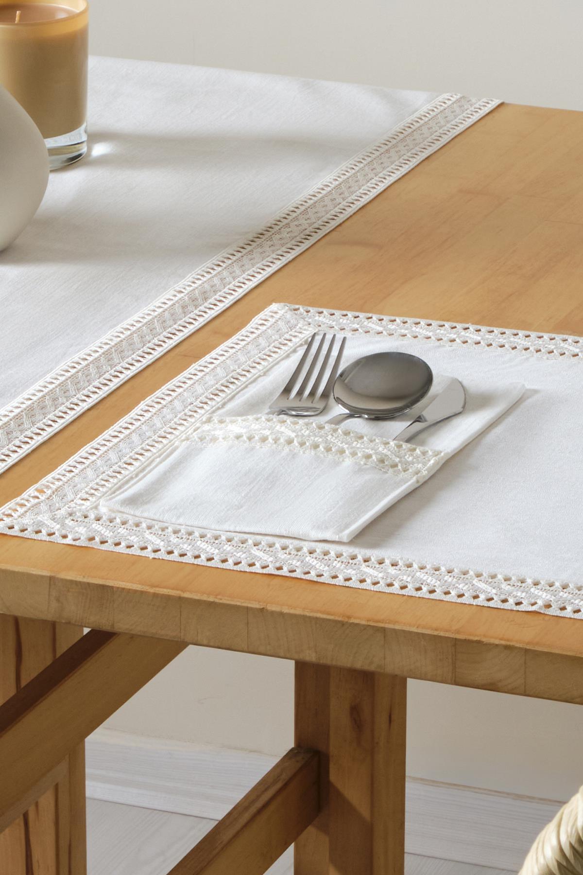 Lace white tablecloth and cutlery set with fork, spoon, and knife in a napkin holder on a wooden table