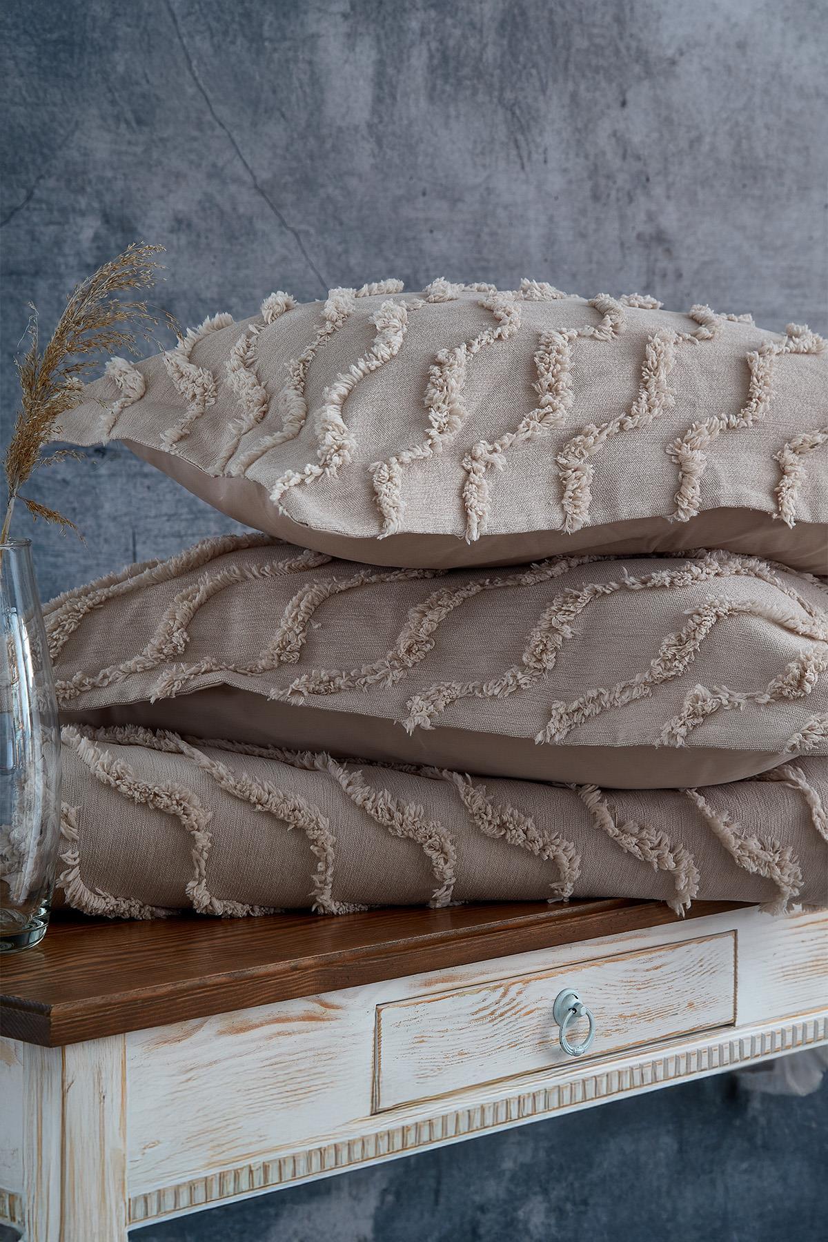 Linen-textured, natural-toned double bedspread and pillow with a wavy pattern