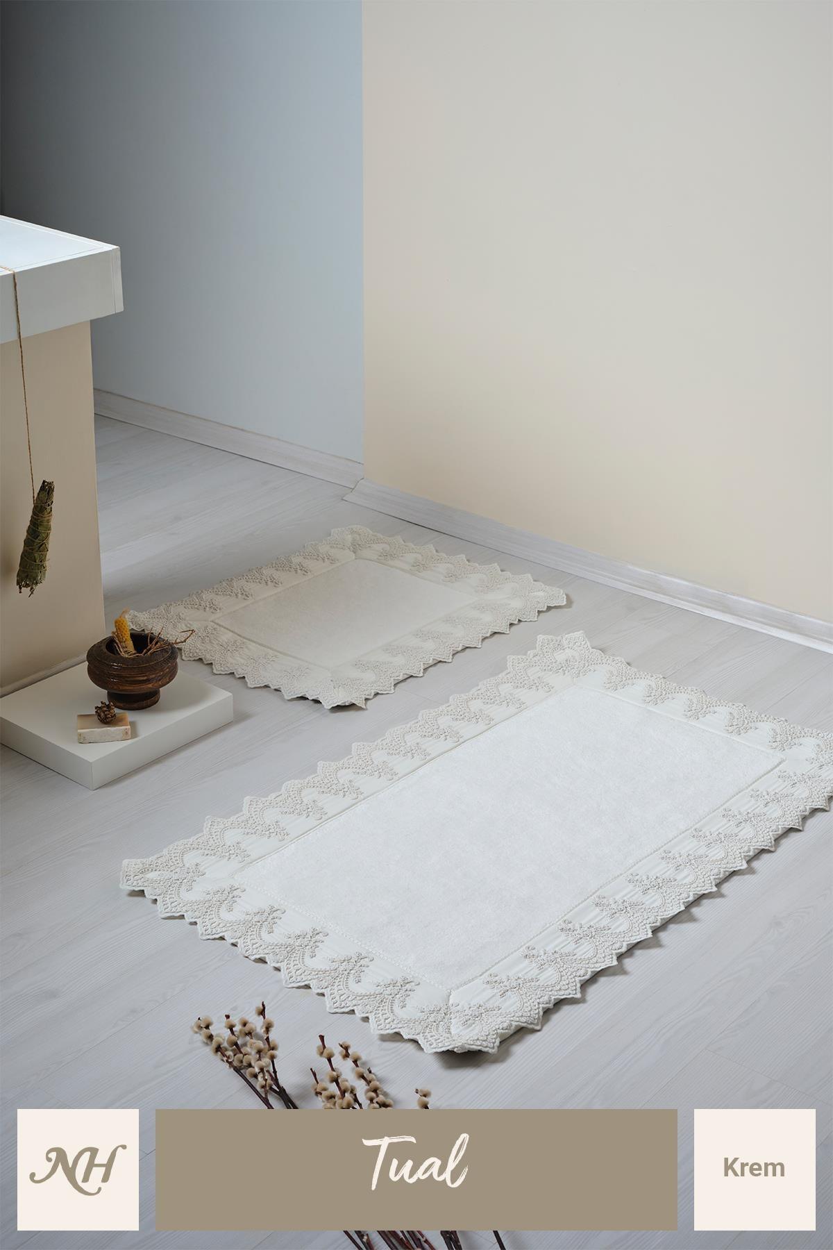 Cream-colored, lace-embroidered two-piece bath mat set on a modern and stylish bathroom floor