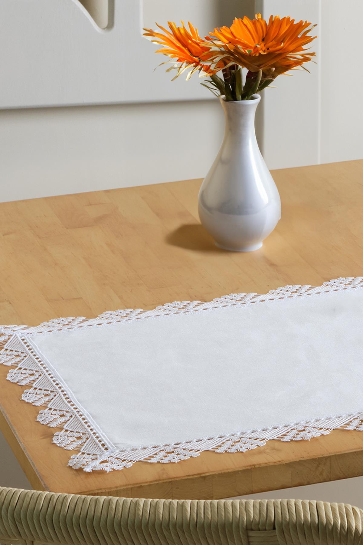 White lace-edged table runner and placemat with a decorative vase on a wooden table