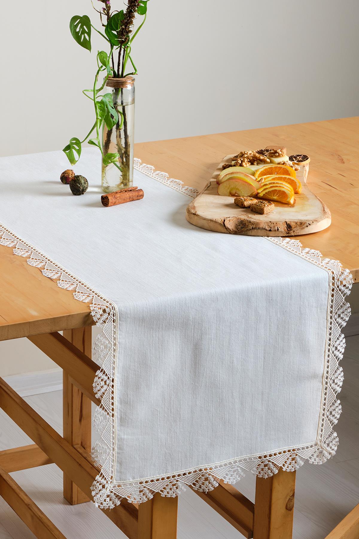 White lace table runner, table decorated with fruit and an ornamental plant on a wooden table