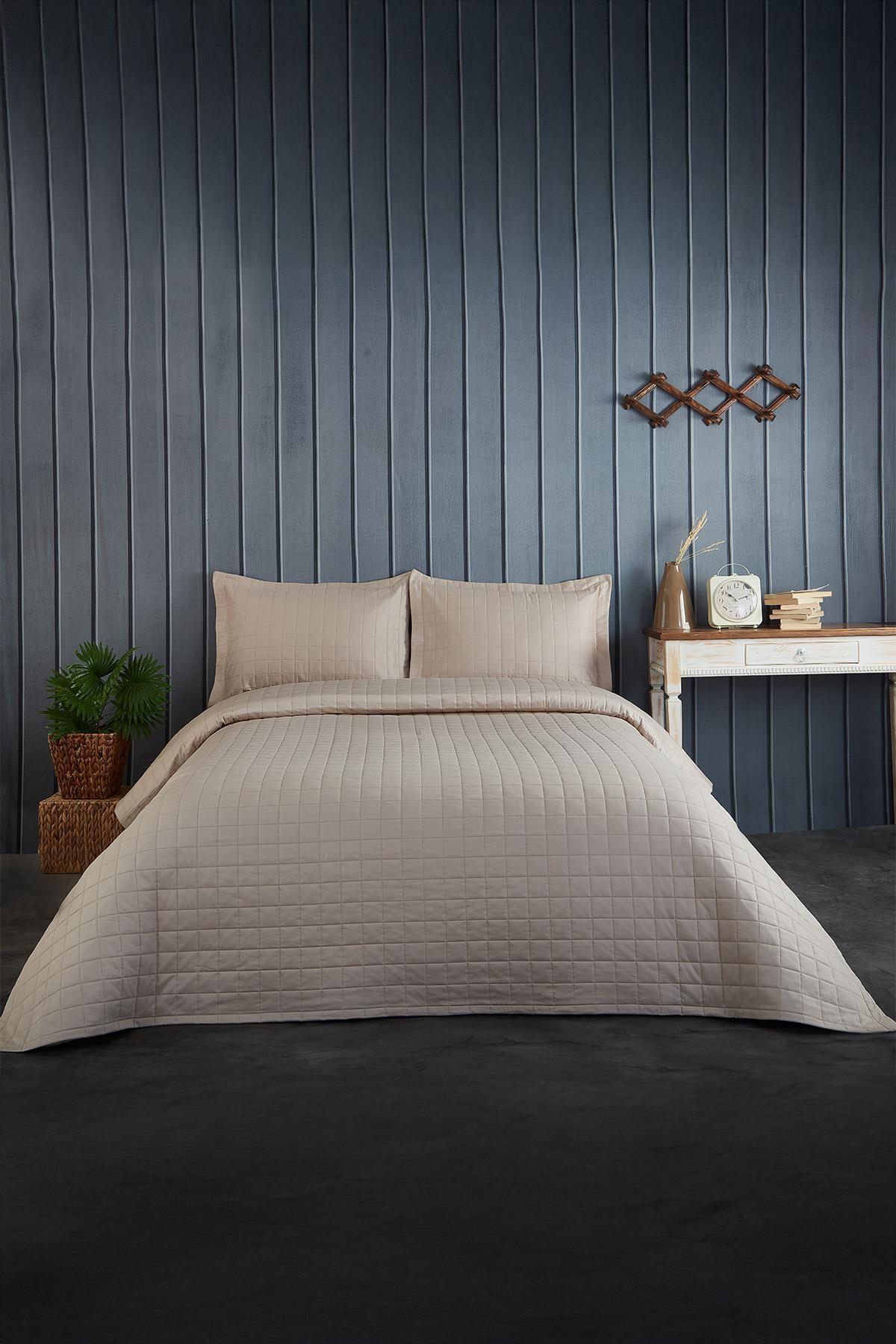 Quilted double bedspread in a modern bedroom, beige, with pillows