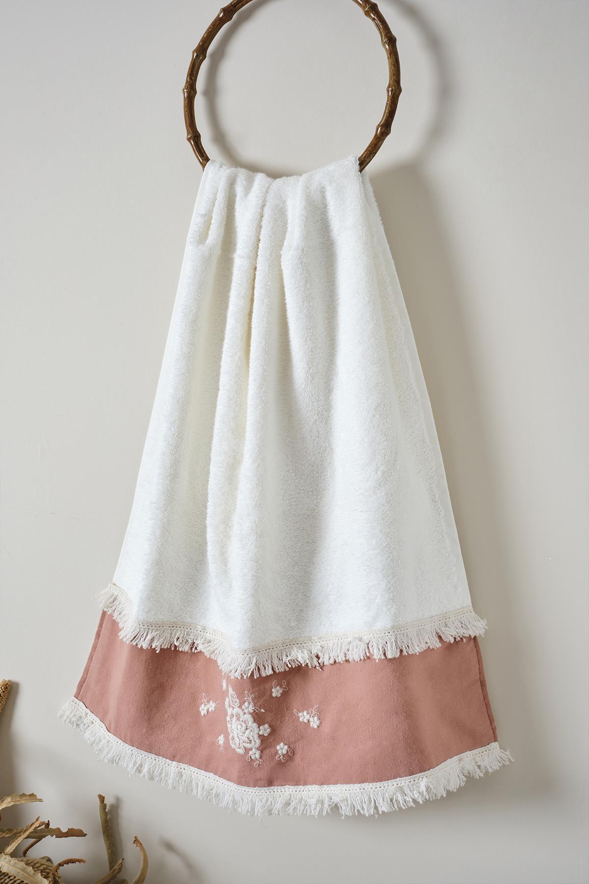 White and powder-colored small embroidered towel with lace edges hanging on a hook