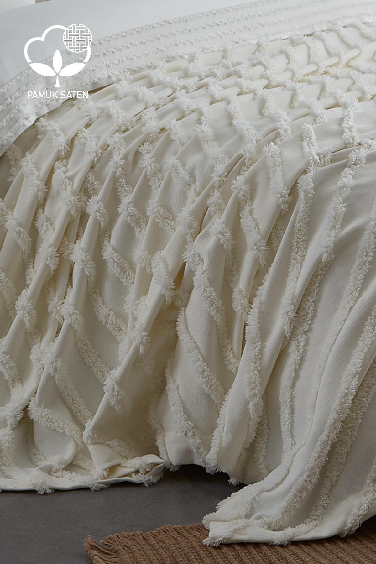Cream-colored cotton sateen, textured double duvet cover and bedspread set laid out on the bed