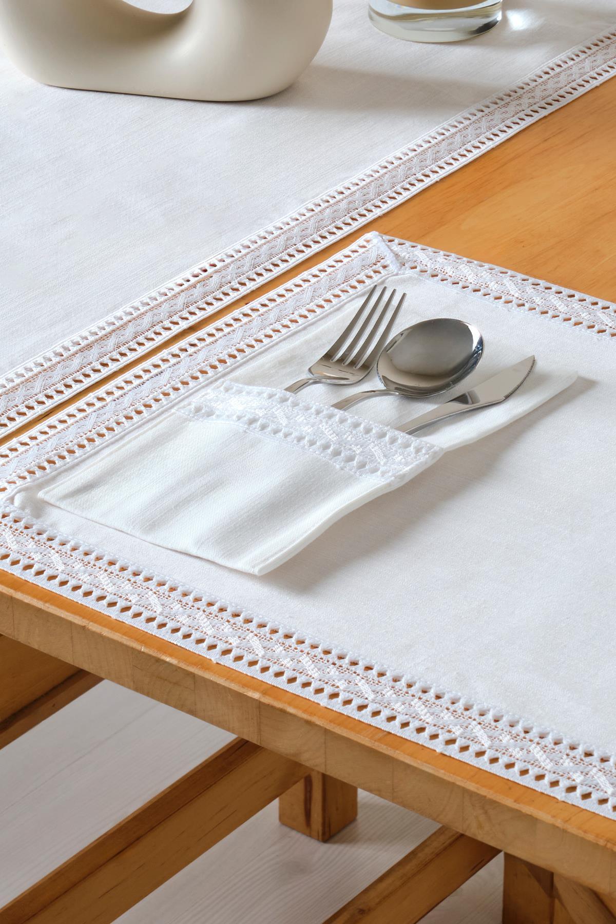 Elegant table decoration with a white lace tablecloth and a cutlery set in a pocket