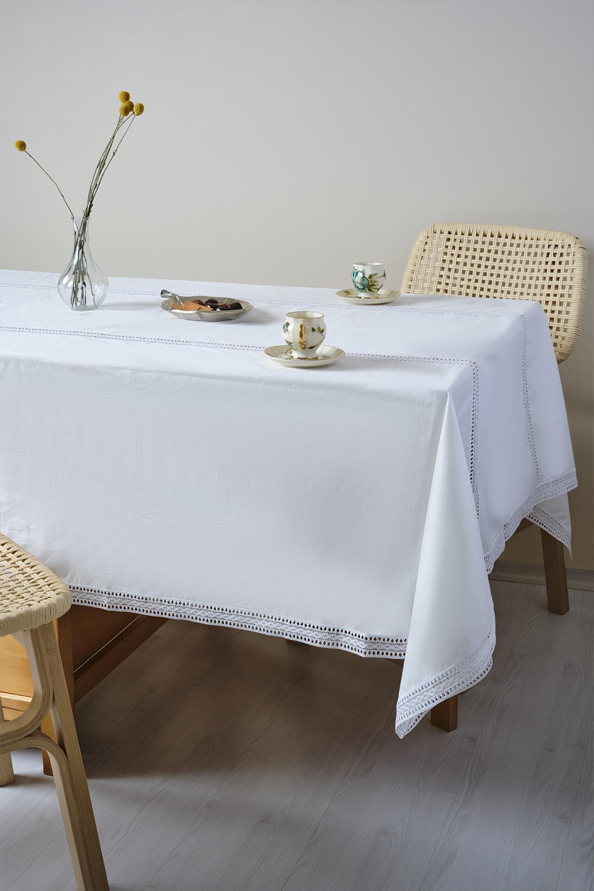 Table covered with a white tablecloth, featuring porcelain cups and a floral vase on top