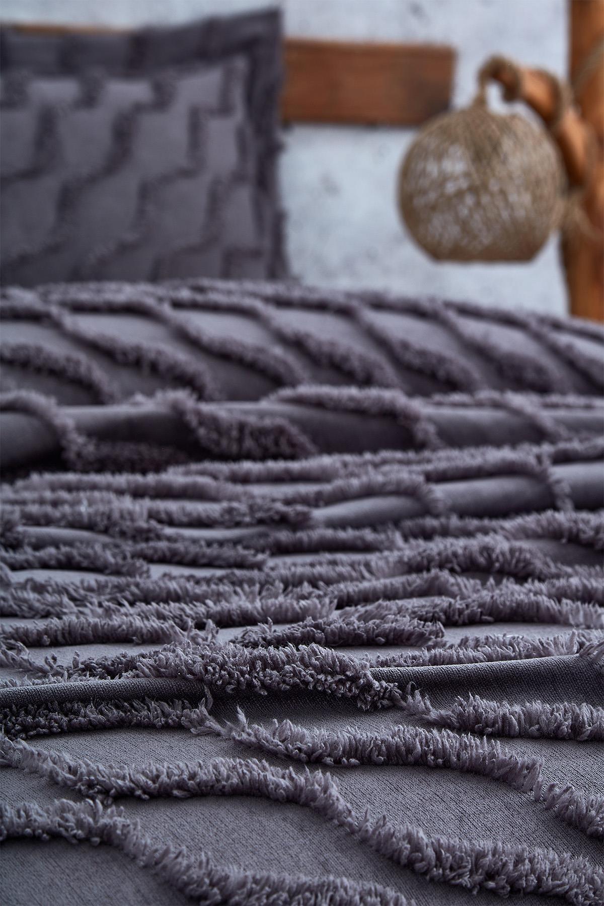 Close-up of a linen-textured, single-size purple bedspread with matching pillow details.
