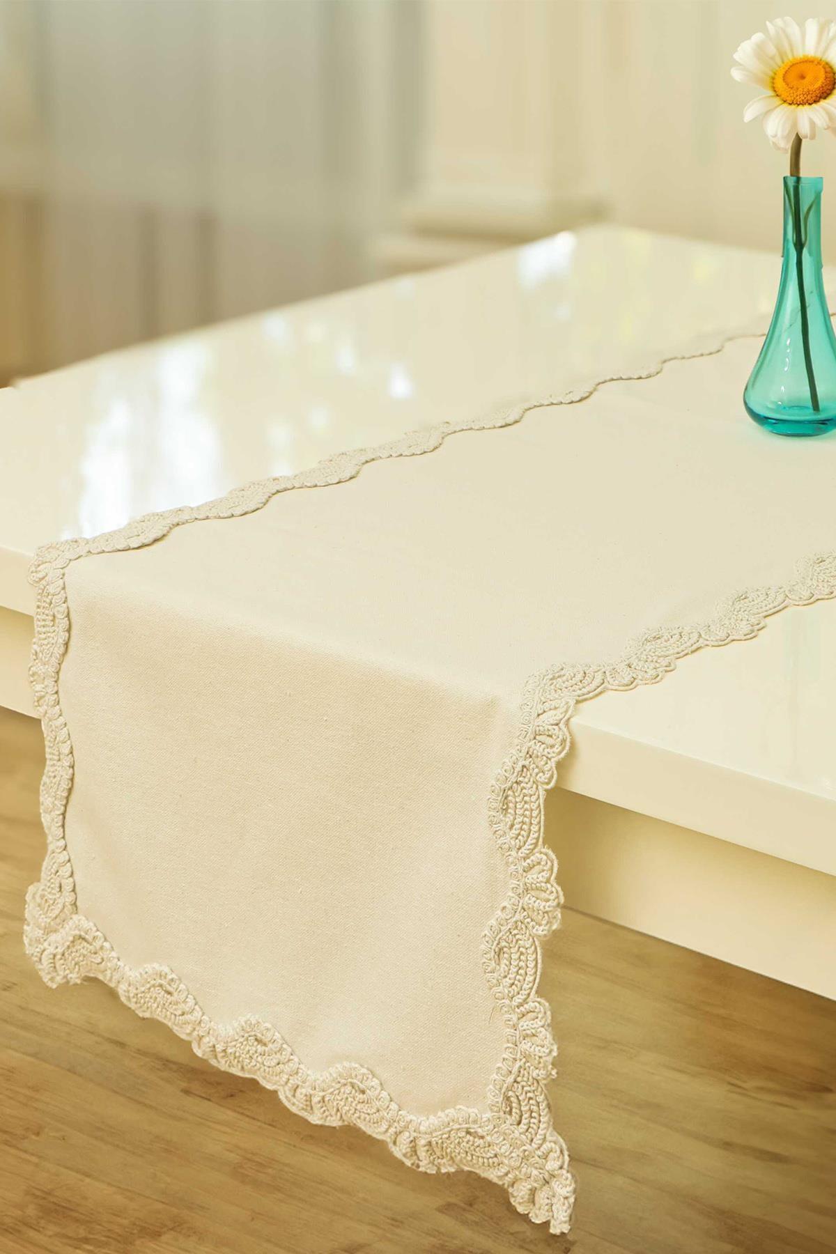 Cream-colored table runner with lace edges, decorative stylish tablecloth on a white table